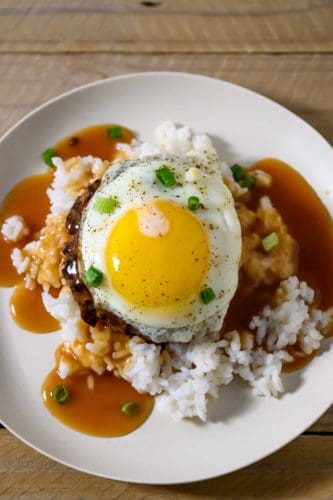 Loco Moco Plate with white rice topped with a beef patty, topped with brown gravy, topped with an egg on a plate.