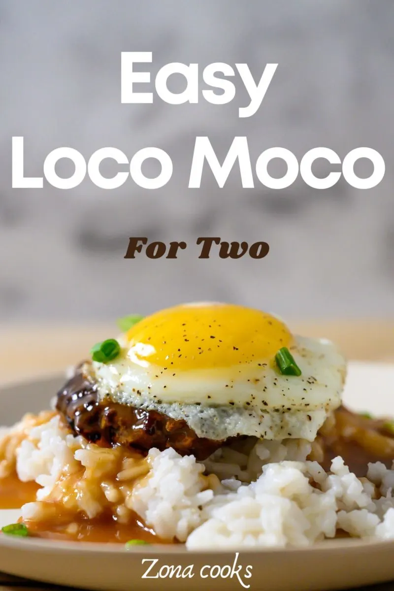 Authentic Loco Moco with white rice topped with a beef patty, topped with brown gravy, topped with an egg on a plate.