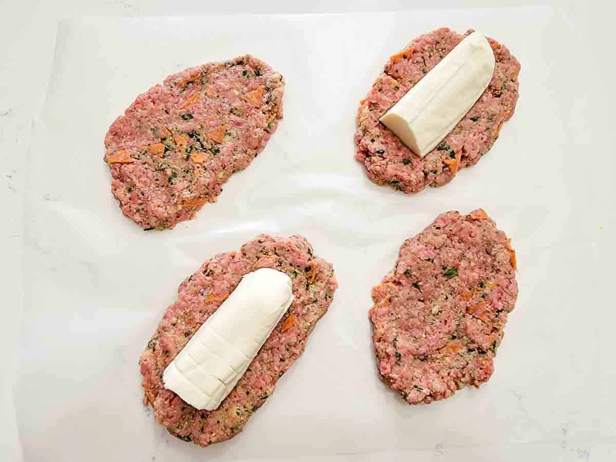 two long fresh mozzarella slices on two meatloaf patties.
