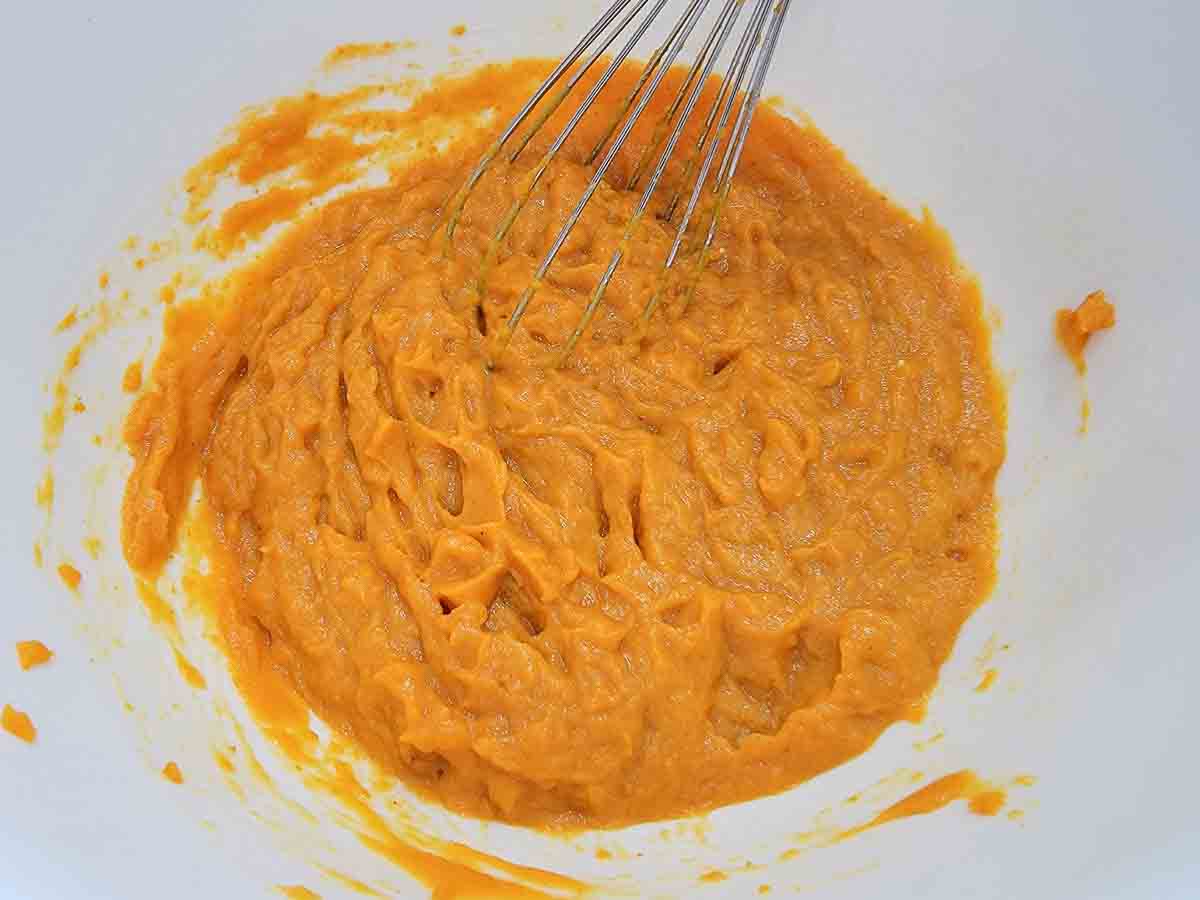 eggs and pumpkin puree added to dray ingredients in a bowl.