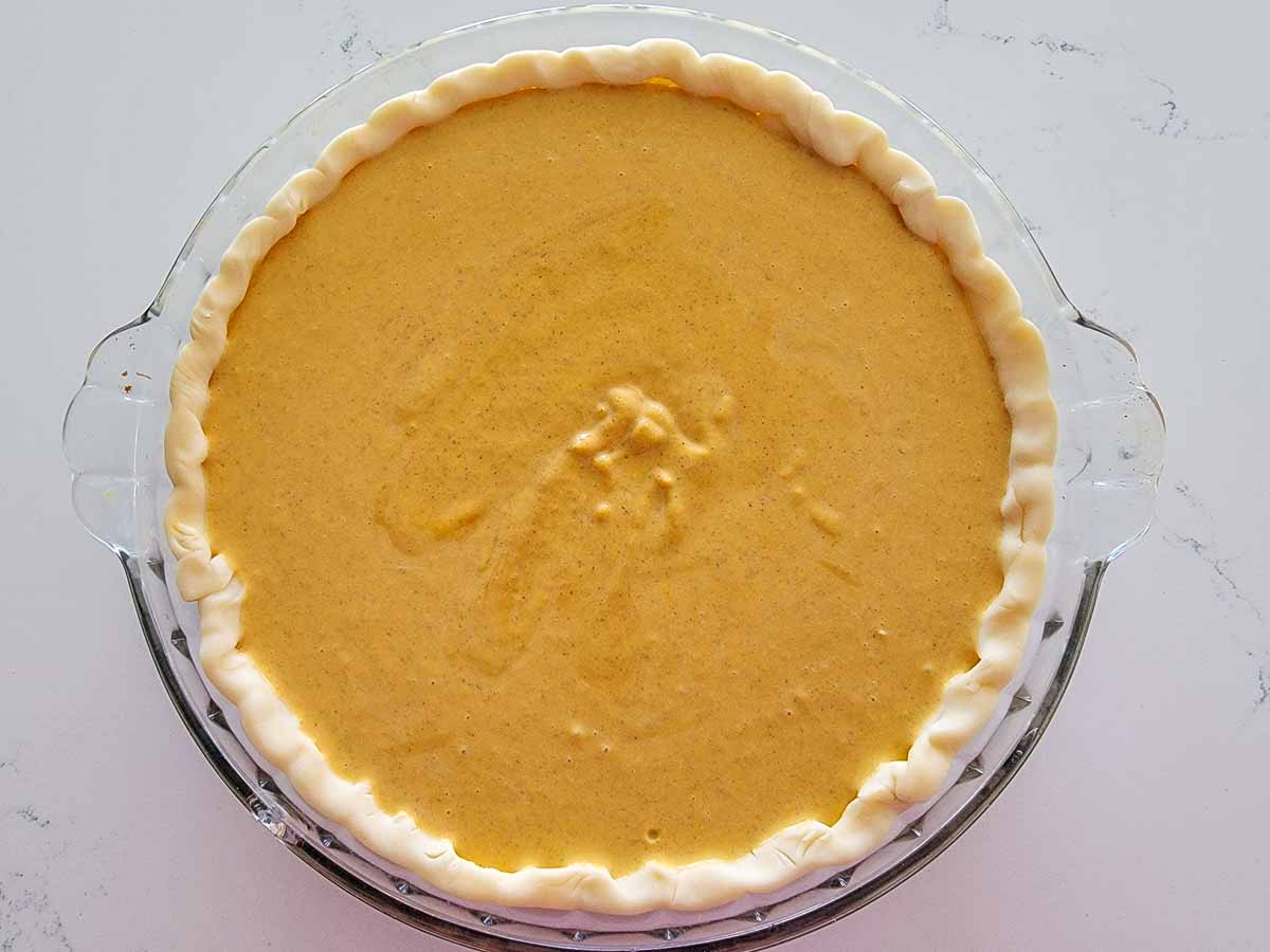 pumpkin filling poured into prepared pie dough.