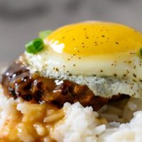 Easy Loco Moco with white rice topped with a beef patty, topped with brown gravy, topped with an egg on a plate.