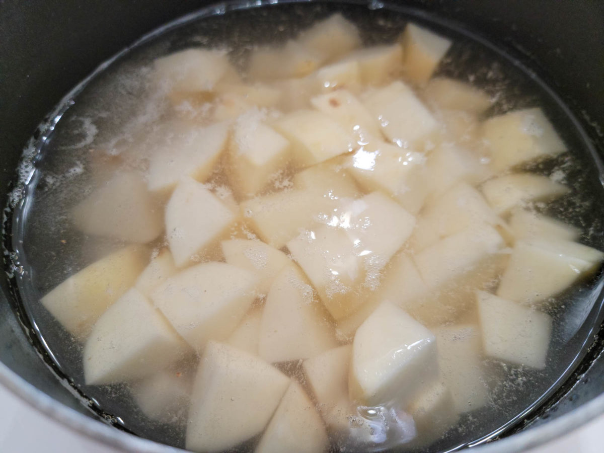 peeled and diced potatoes cooking in a pan.