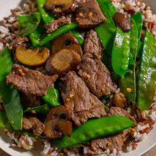 Beef and Snow Pea Stir Fry over rice on a plate.