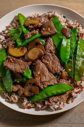 Beef and Snow Pea Stir Fry over rice on a plate.