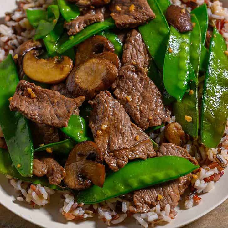 Beef and Snow Pea Stir Fry over rice on a plate.