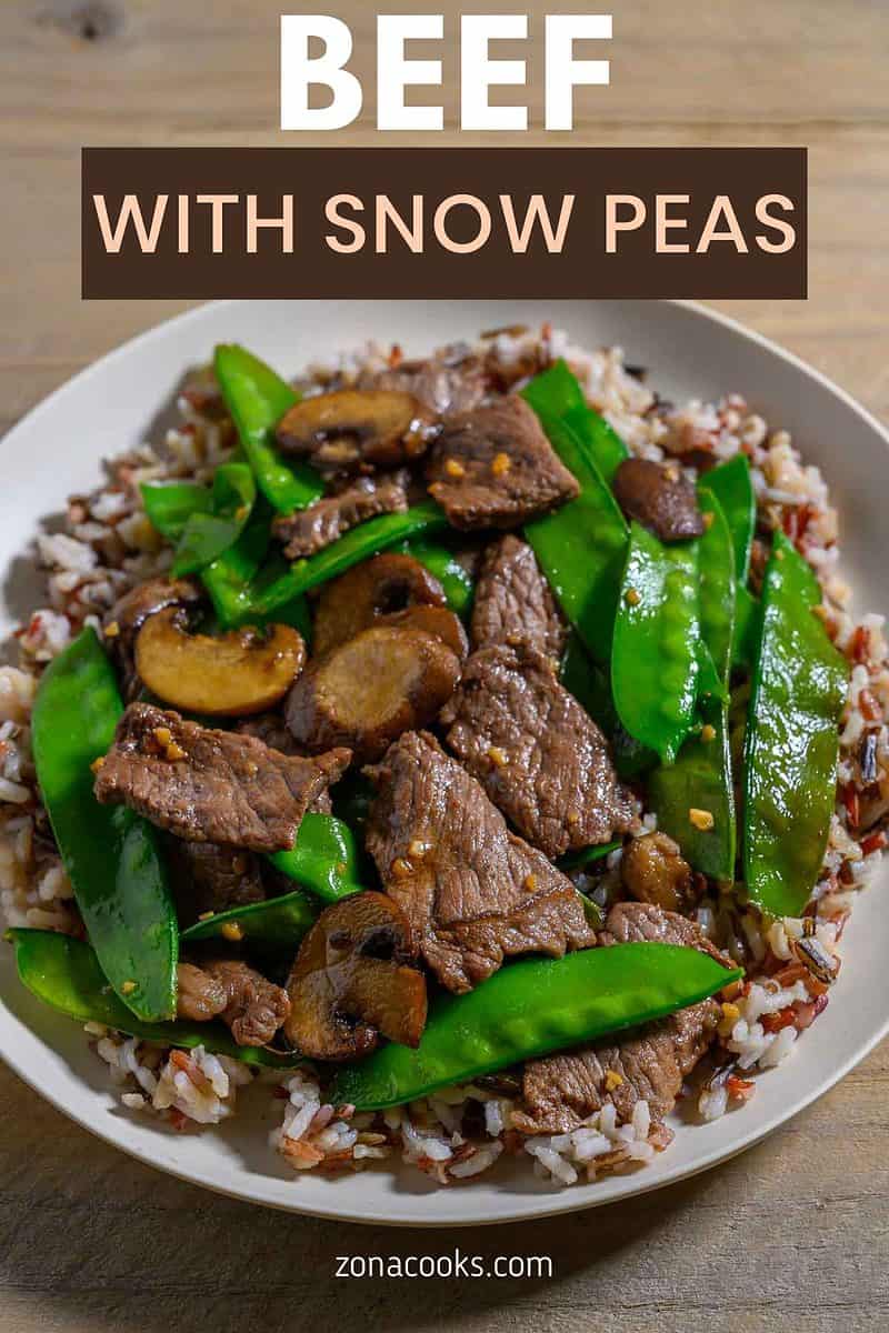 Beef with Snow Peas over rice on a plate.