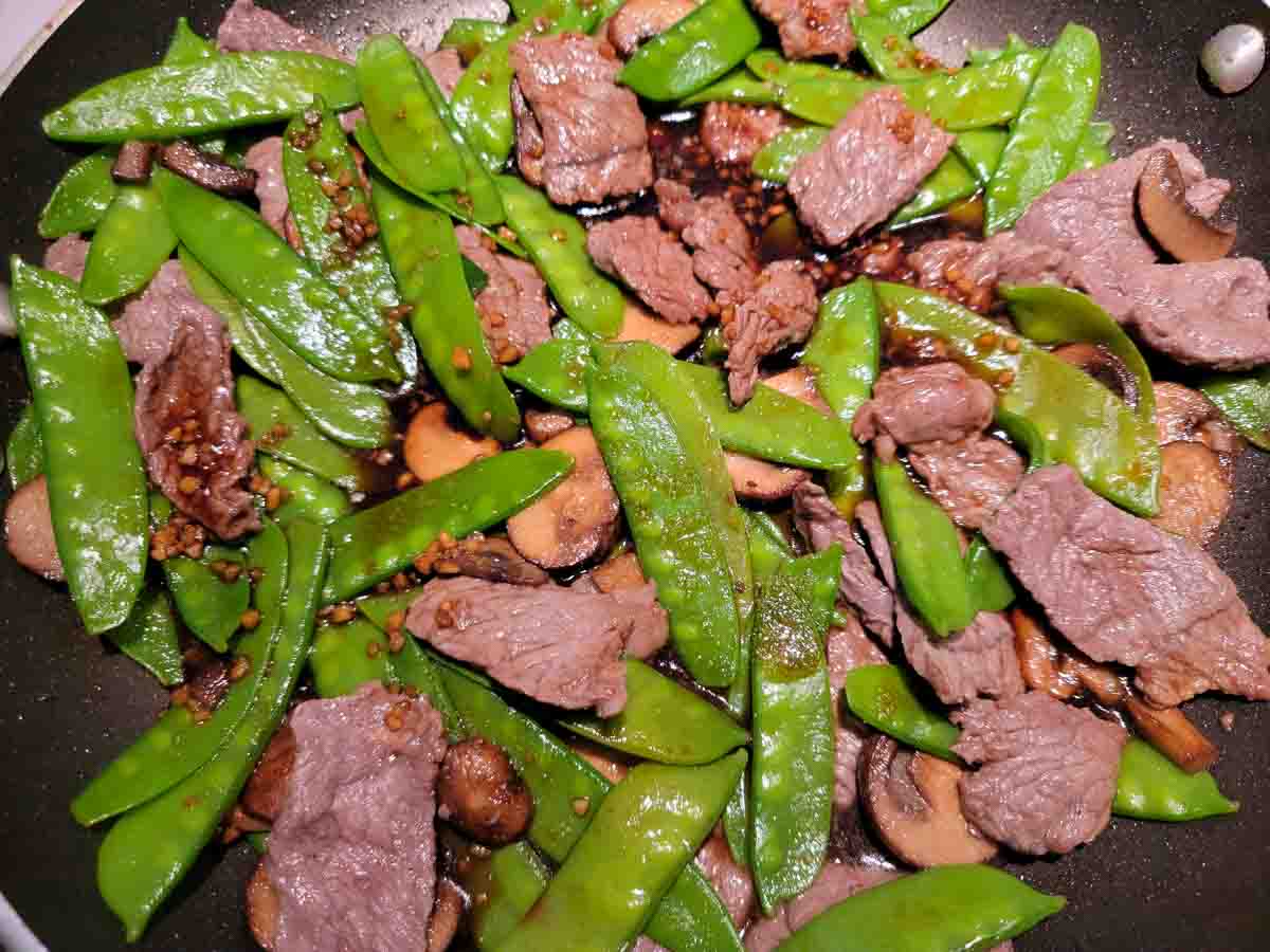 snow pea beef cooking in a pan.