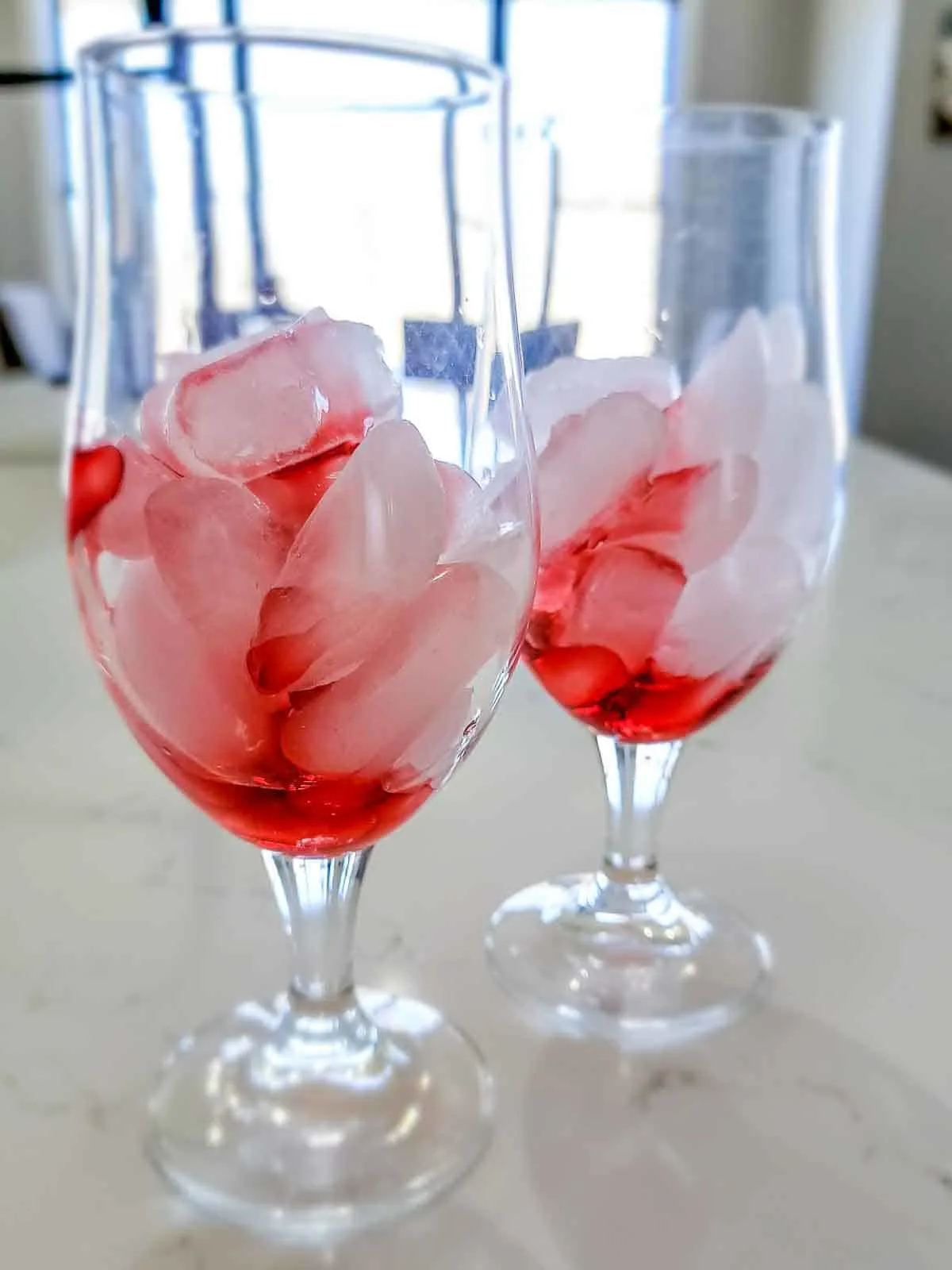 a glass filled with ice cubes and strawberry syrup.