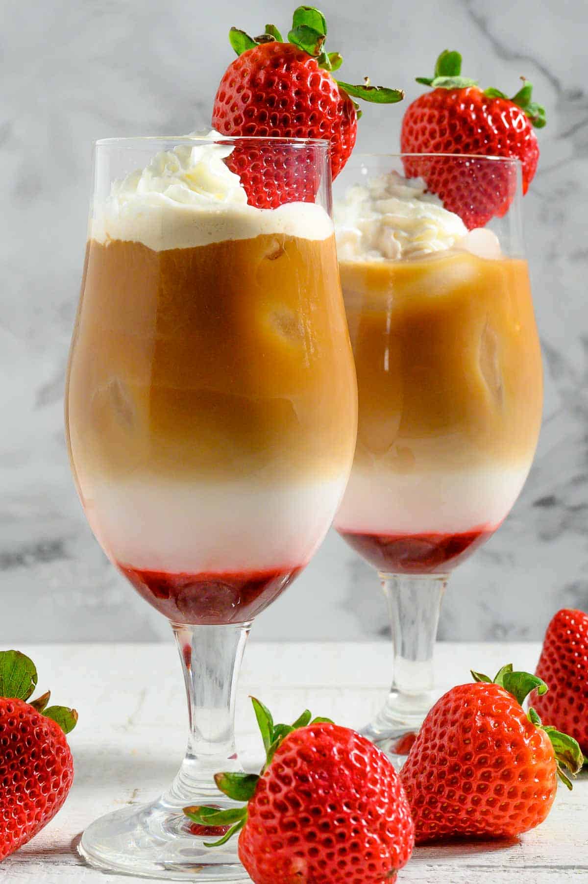 Easy Iced Strawberry Latte topped with whipped cream and a fresh strawberry.