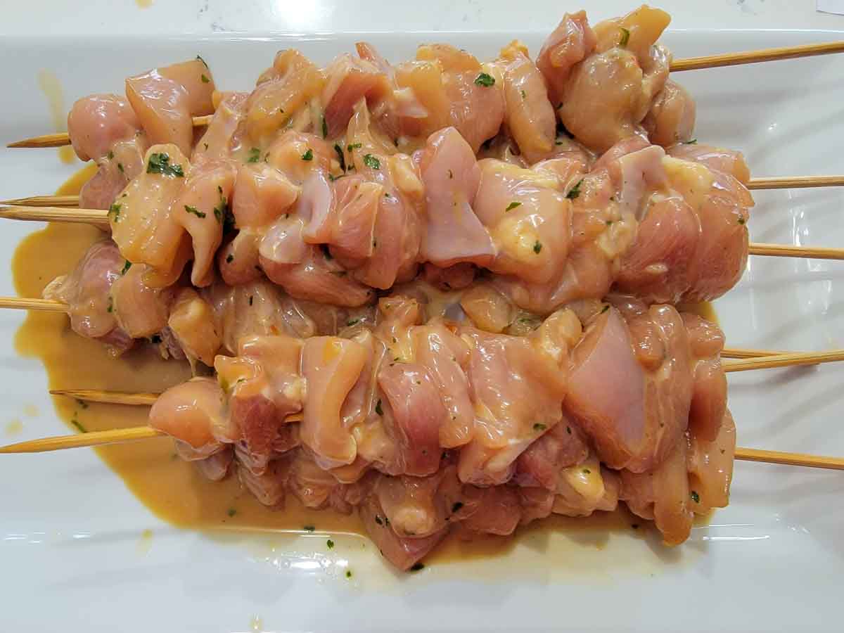 peanut sauce marinated chicken cubes threaded onto skewers.