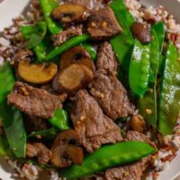 Beef and Snow Pea Stir Fry over rice on a plate.