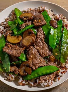 Beef and Snow Pea Stir Fry over rice on a plate.