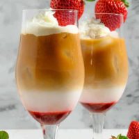 Easy Iced Strawberry Latte topped with whipped cream and a fresh strawberry.