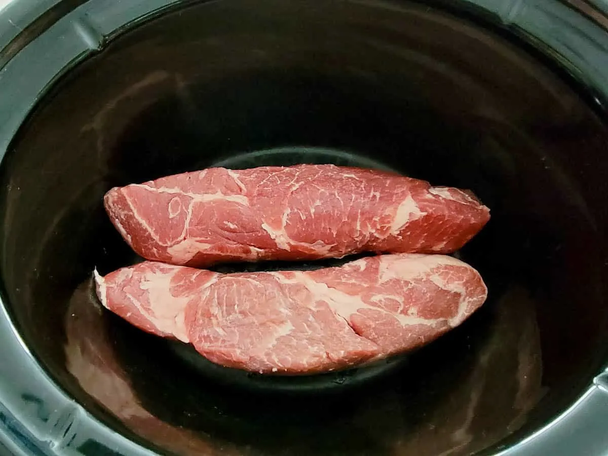 two country-style pork ribs in the bottom of a crock pot.