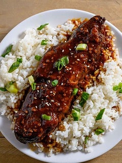 Asian Country Style Ribs over rice on a plate.