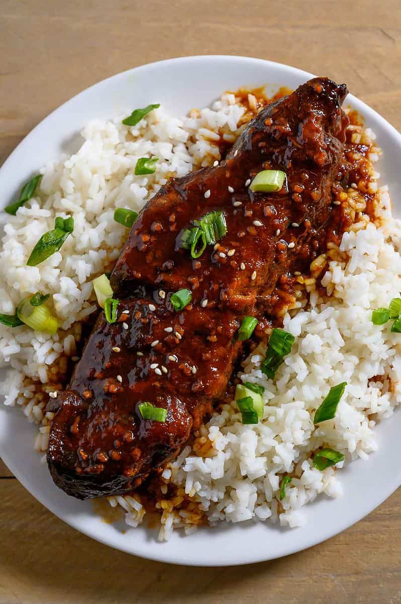 Asian Country Style Ribs over rice on a plate.