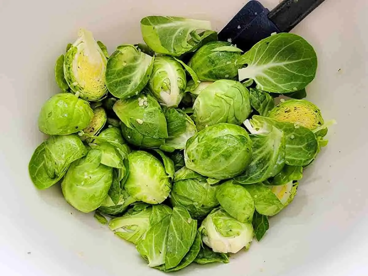 brussels sprouts mixed in oil mixture in a bowl.