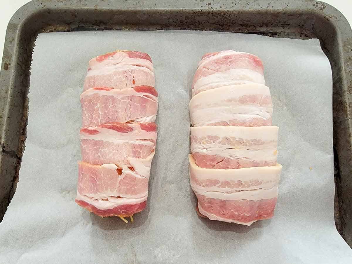 two bacon-wrapped mini ground chicken meatloaves on a baking sheet.