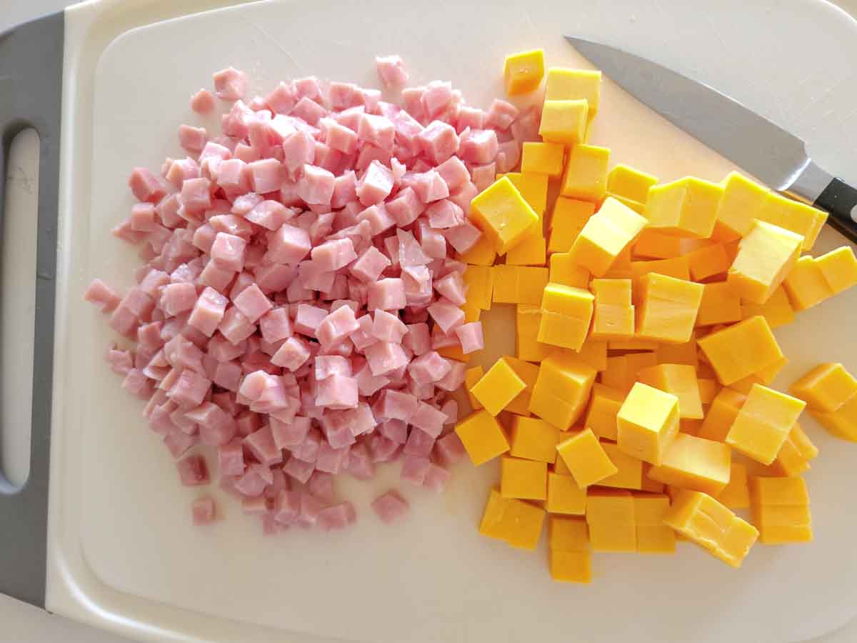 diced ham and cheddar cheese on a cutting board.