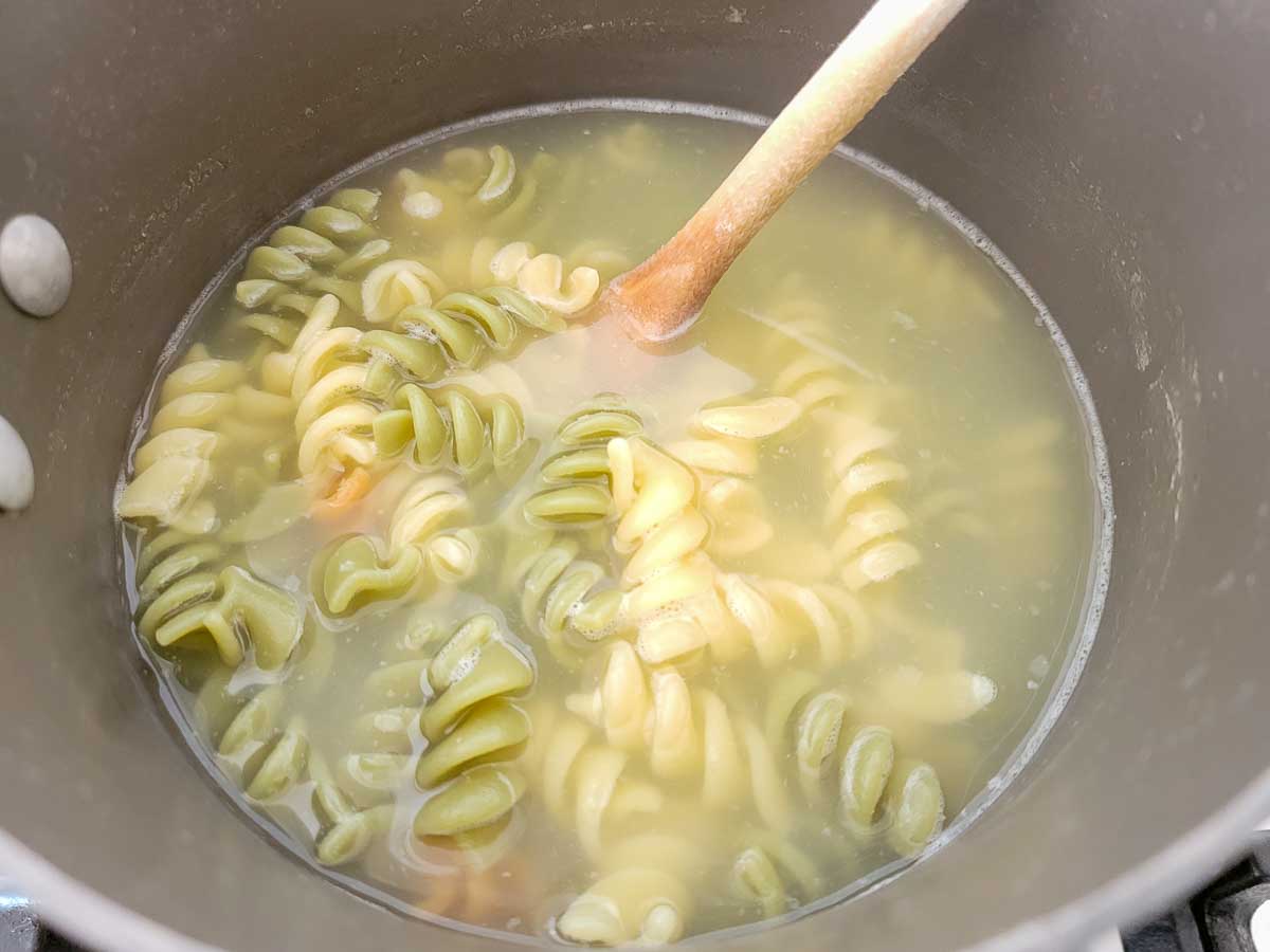 tri-color rotini pasta cooking in a pan.