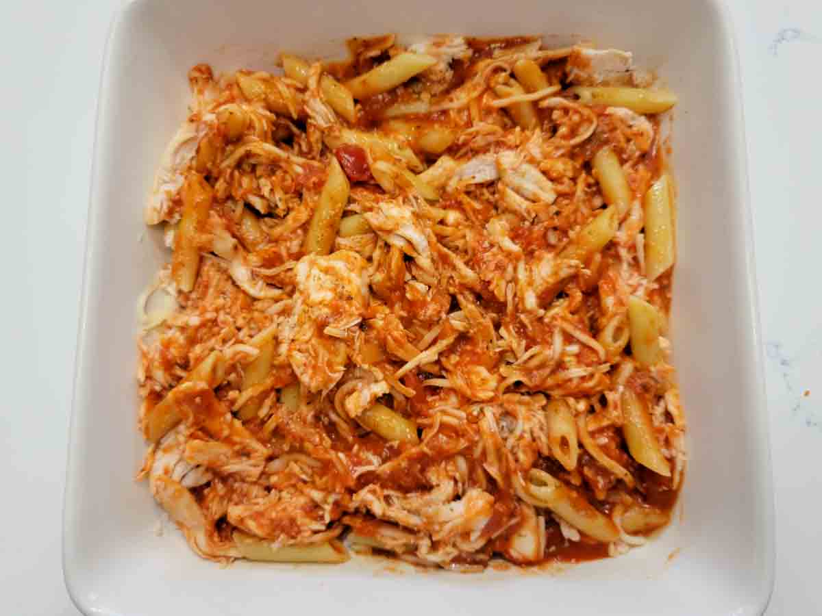penne pasta, chicken, and sauce in a baking dish.