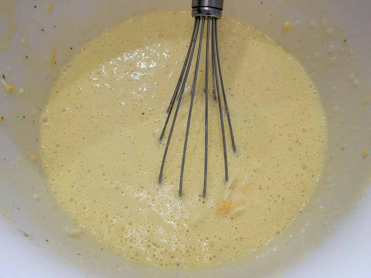 eggs, heavy cream, and shredded mozzarella and cheddar cheese, plus veggies, salt, and pepper whisked in a bowl.