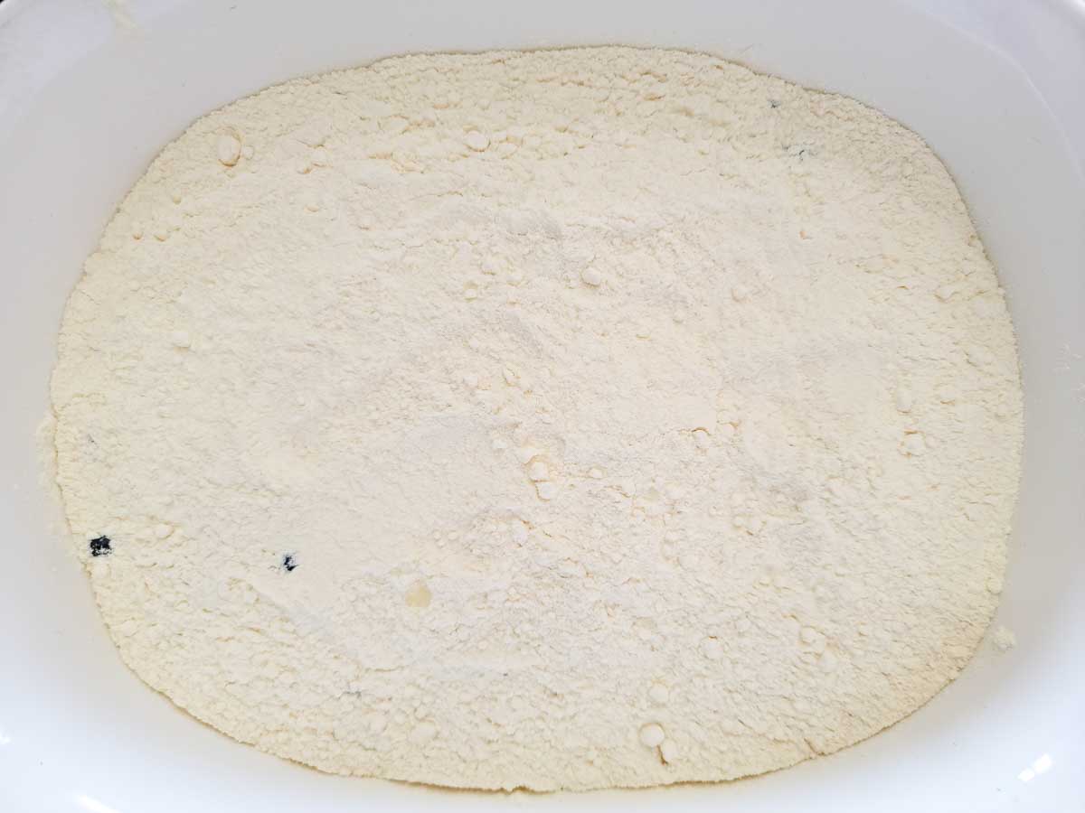 dry cake mix over blueberries in a large dish.