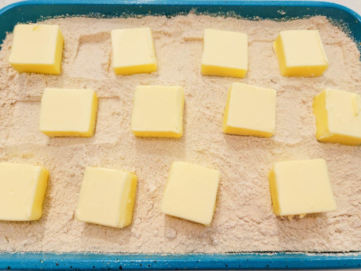 pats of butter and spice cake mix over apple pie filling in a cake pan.