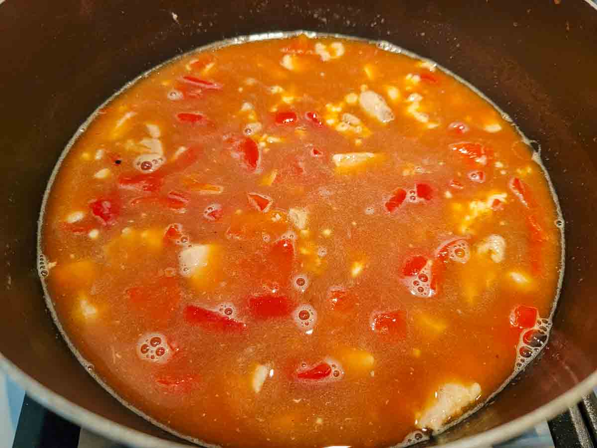 chicken soup cooking in a pan.