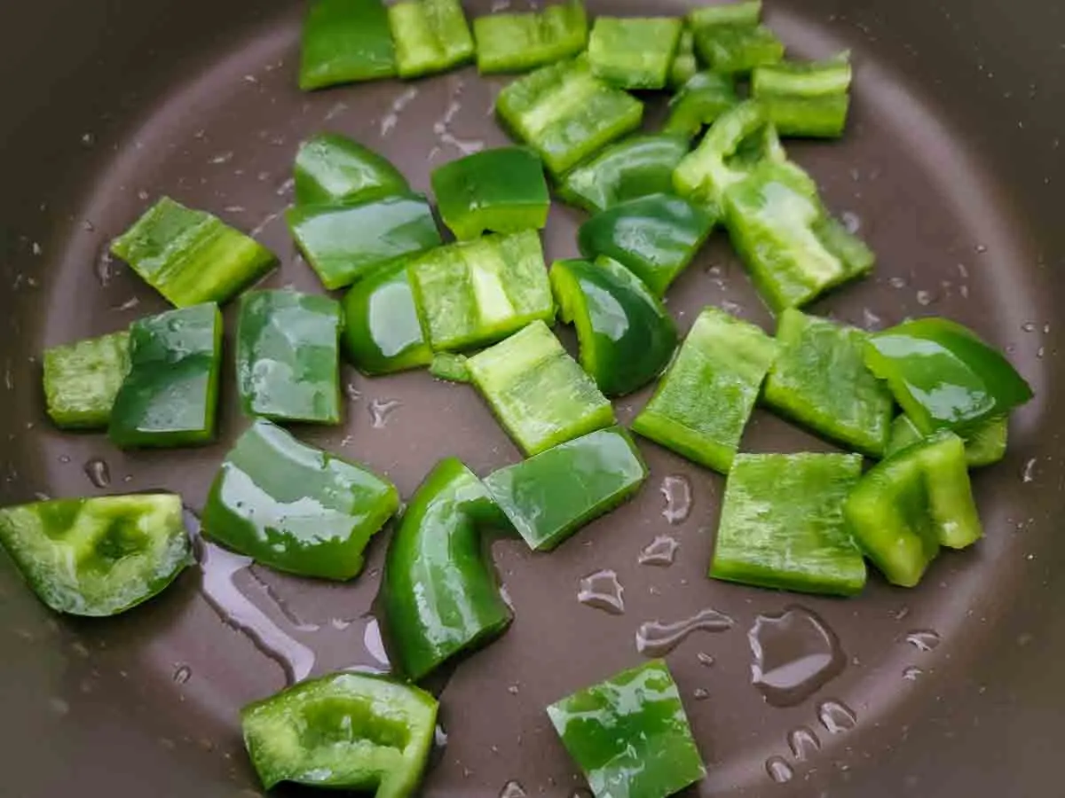 dice green pepper cooking in a pan.