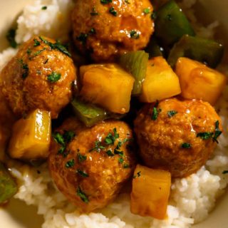 Teriyaki Pineapple Meatballs over rice in a bowl.