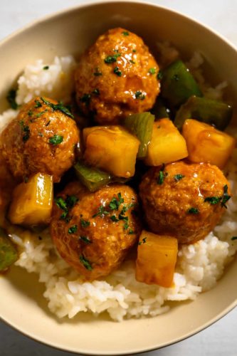 Teriyaki Pineapple Meatballs over rice in a bowl.