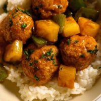 Teriyaki Pineapple Meatballs over rice in a bowl.