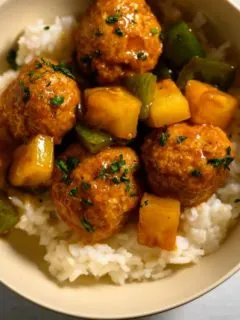 Teriyaki Pineapple Meatballs over rice in a bowl.