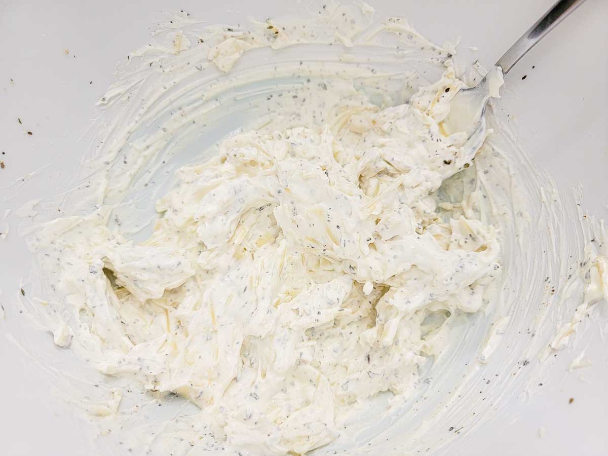 mozzarella, sour cream, 1/4 cup of Parmesan, oregano, basil, garlic powder, salt and pepper in a bowl.