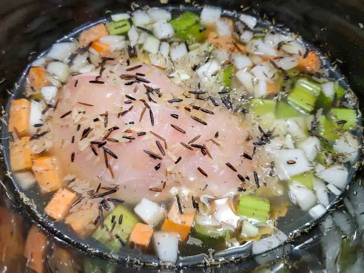 boneless skinless chicken, onion, carrots, celery, minced garlic, salt, pepper, dried thyme, bay leaf, low-sodium chicken broth, and wild rice-brown rice blend in a slow cooker crockpot.