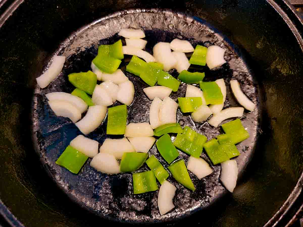 green pepper and onion frying in a skillet.