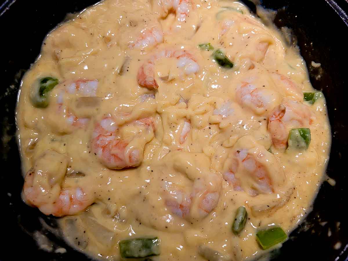 shrimp, soup, water, salt, black pepper, green pepper and onion frying in a skillet.