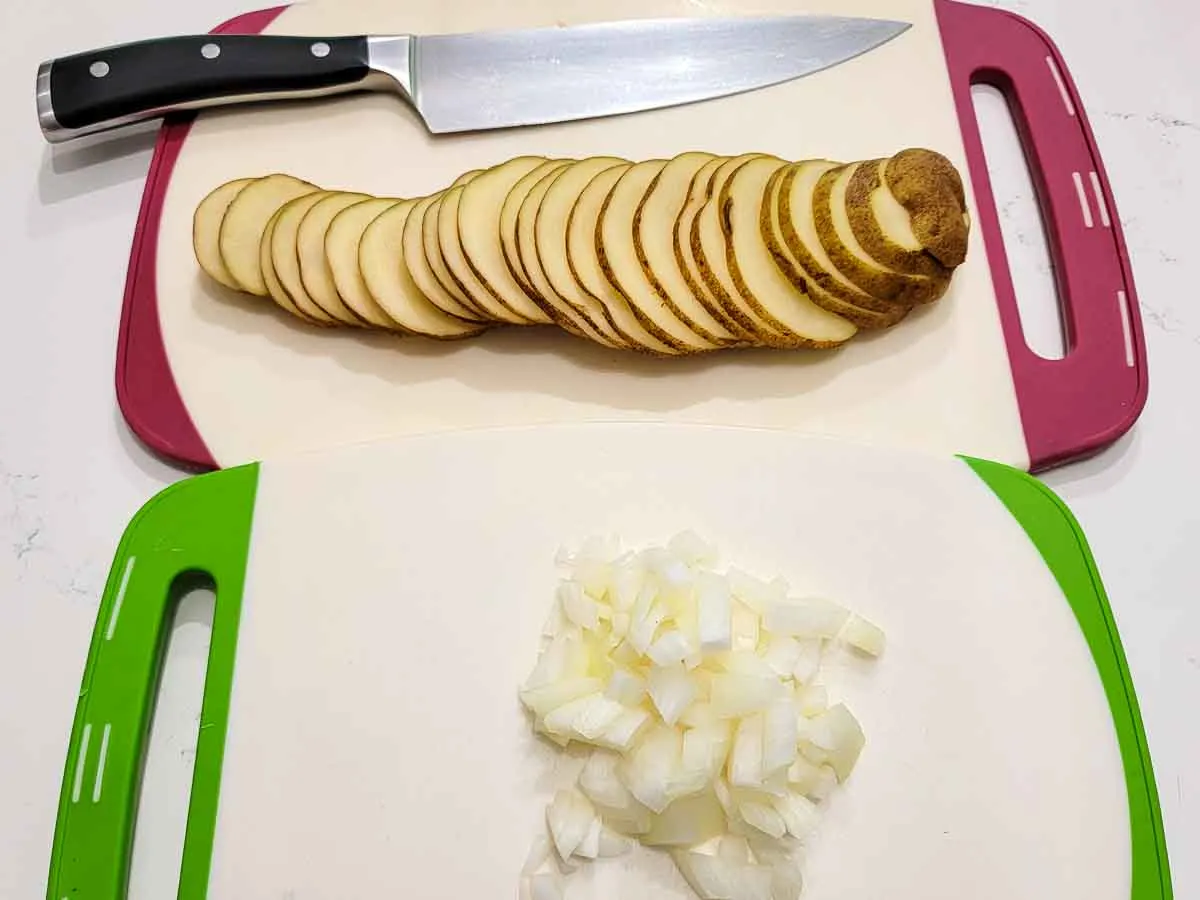 sliced potato and diced onion on two cutting boards.