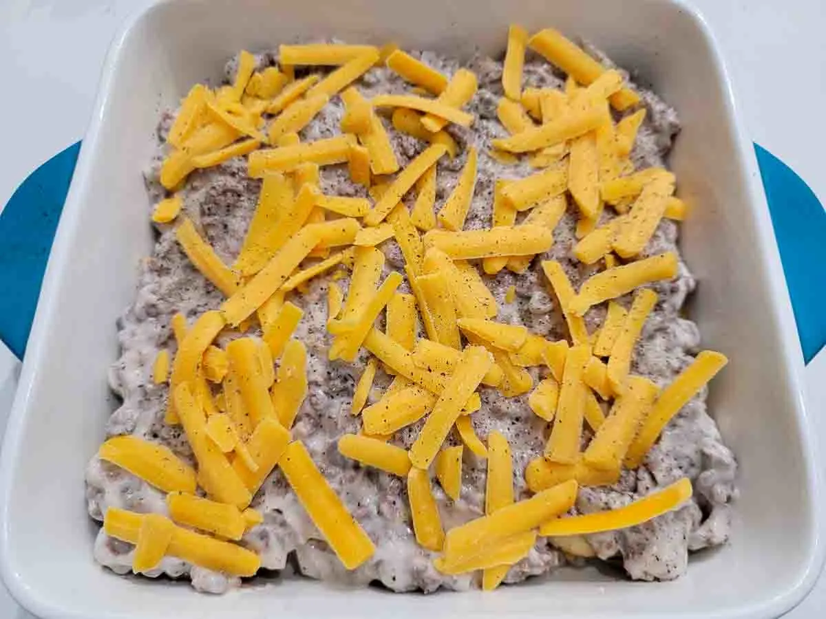 potato slices topped with ground beef, pepper, and cheese in a casserole dish.