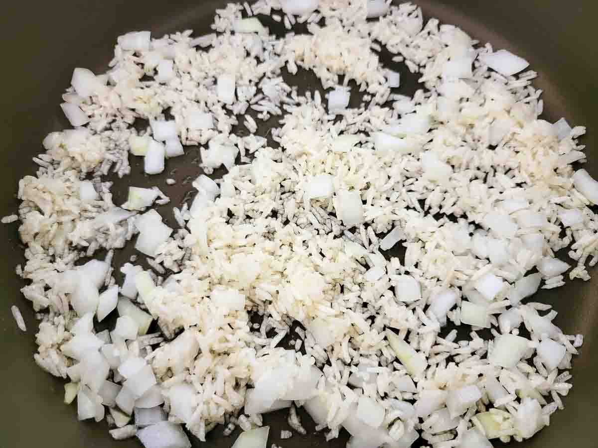 rice and onions cooking in a skillet.