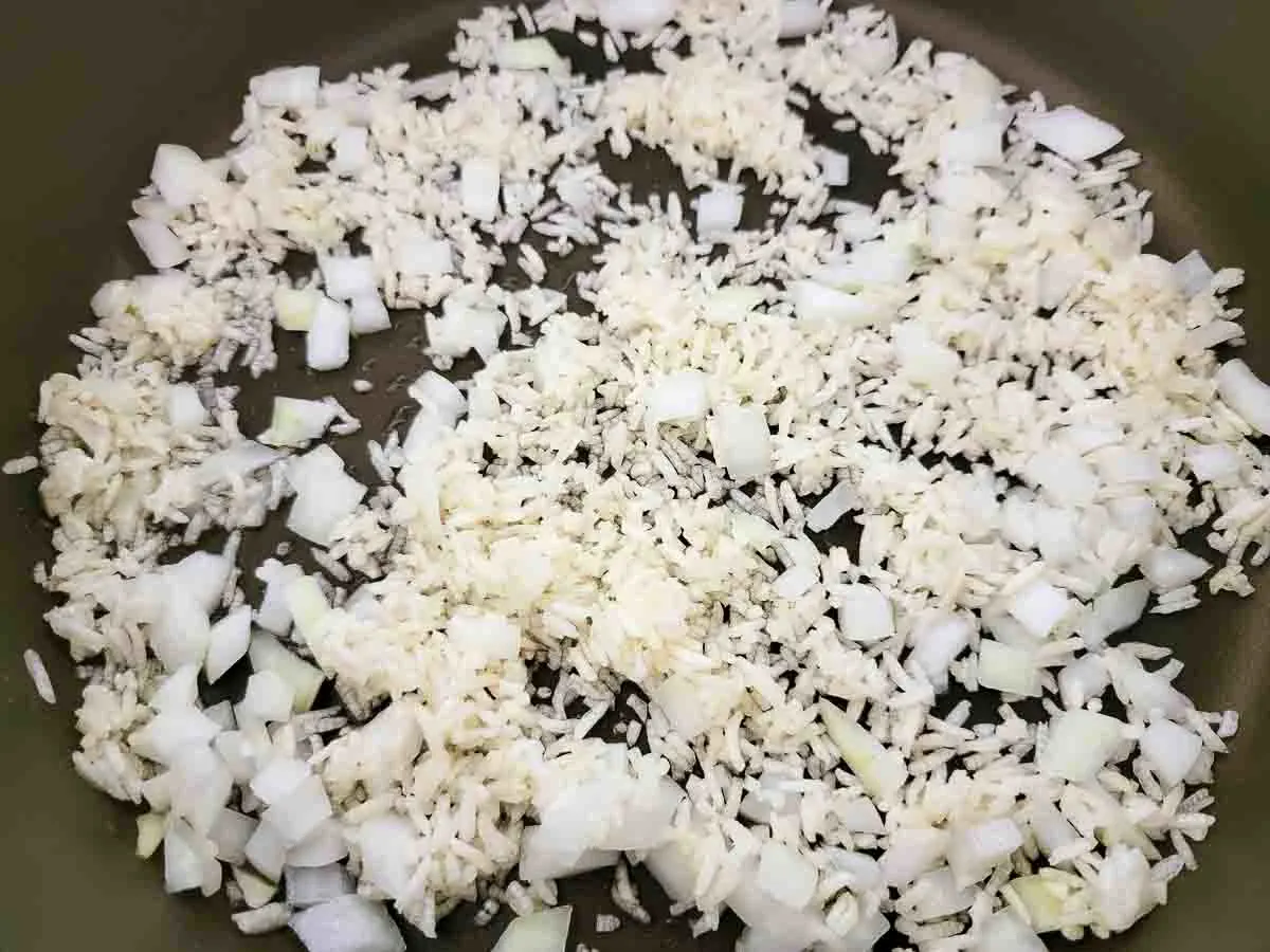 rice and onions cooking in a skillet.