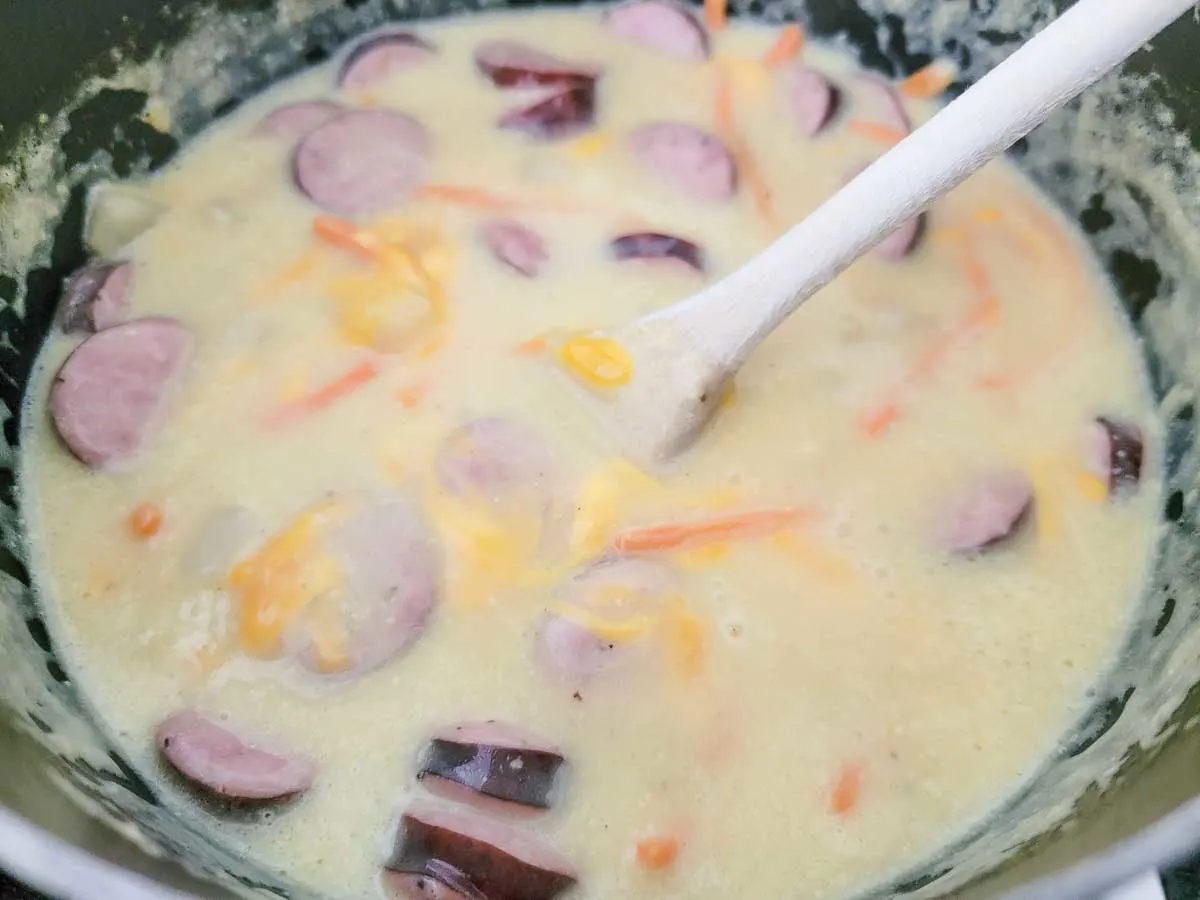 cheddar cheese, sliced kielbasa, carrots, the minced garlic, cream of chicken soup, hash brown potatoes, beer, salt, and pepper in a saucepan.