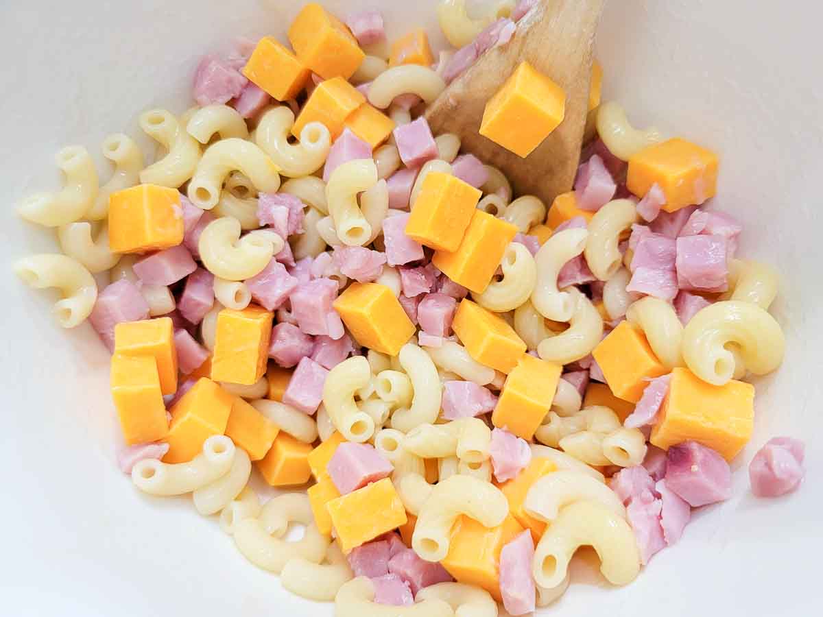 elbow macaroni, diced cheddar cheese, and diced ham in a bowl.