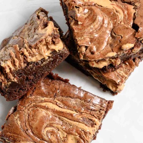 Peanut Butter Brownies stacked on parchment paper.