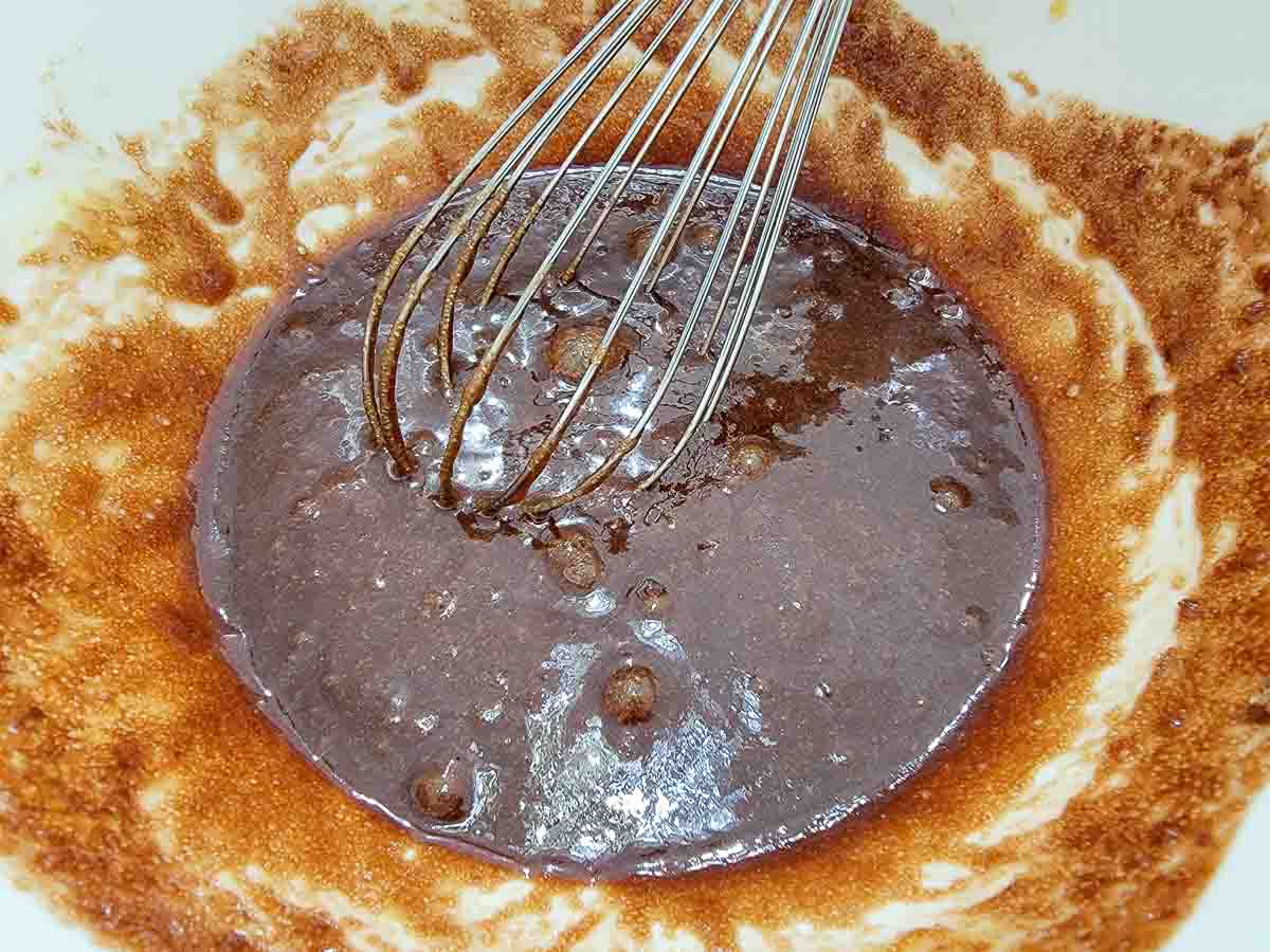 melted chocolate, white sugar, brown sugar, eggs, and vanilla whisked in a bowl.