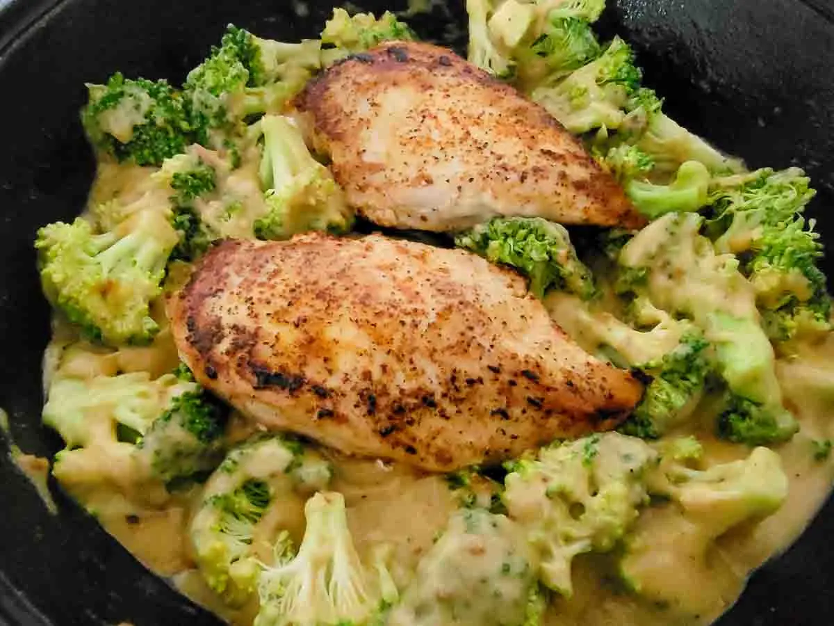 chicken breasts, broccoli, and creamy sauce cooking in a pan.