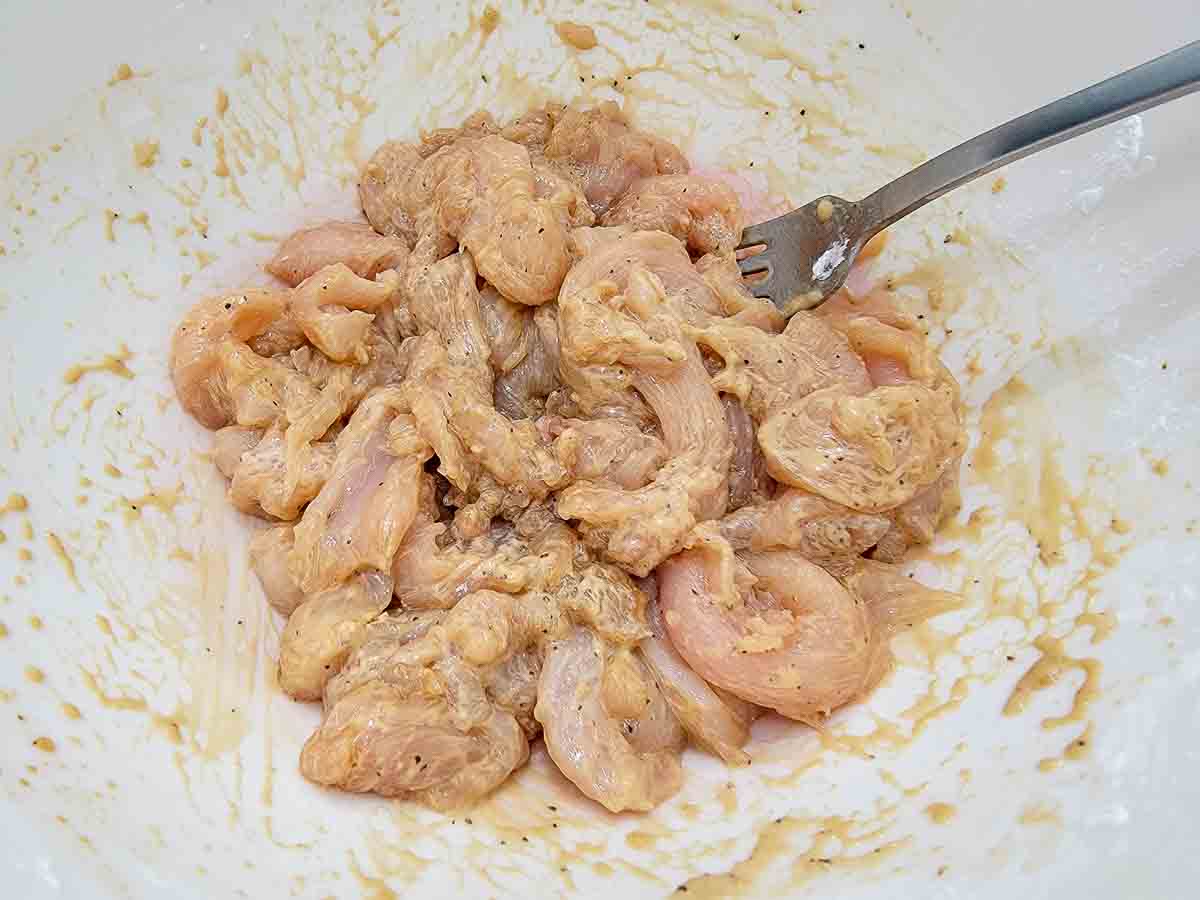 sliced chicken, soy sauce, vegetable oil, cornstarch, pepper, and baking soda mixed in a bowl.