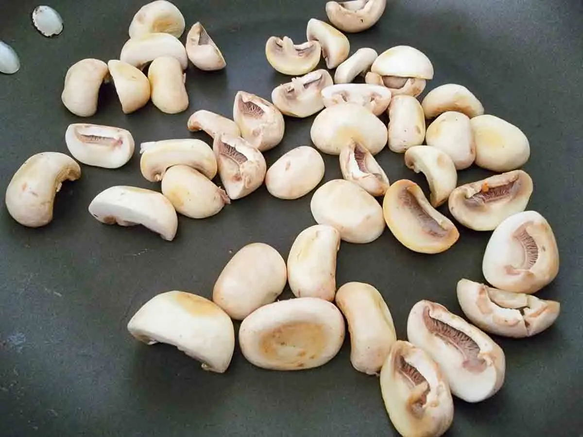 button mushrooms frying in a pan.